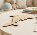 MDF DIY dolphin cutout on a table with plush toys and books in the background