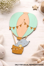 MDF DIY toy hot air balloon with a elephant in a basket on a light wooden surface.