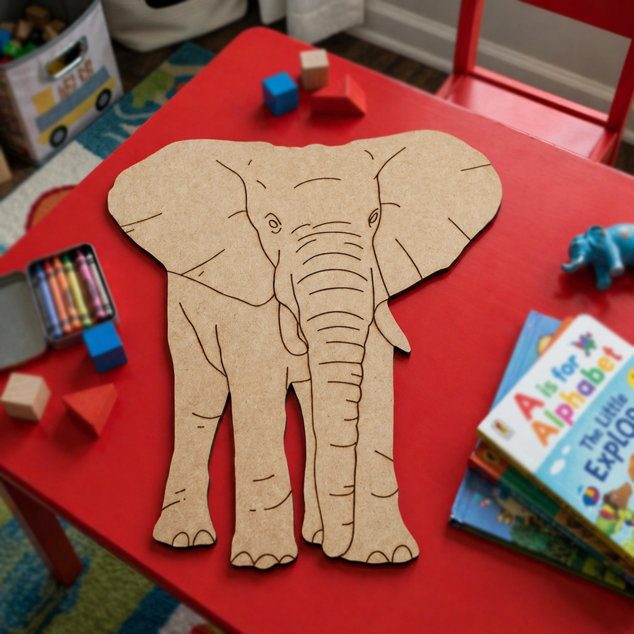 MDF DIY elephant cutout on a red table with children's books and toys in a playroom.
