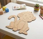 MDF DIY monkey cutout on a table with educational materials in the background