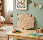 MDF DIY peacock headboard on a child's bedroom wall with toys on a table below.
