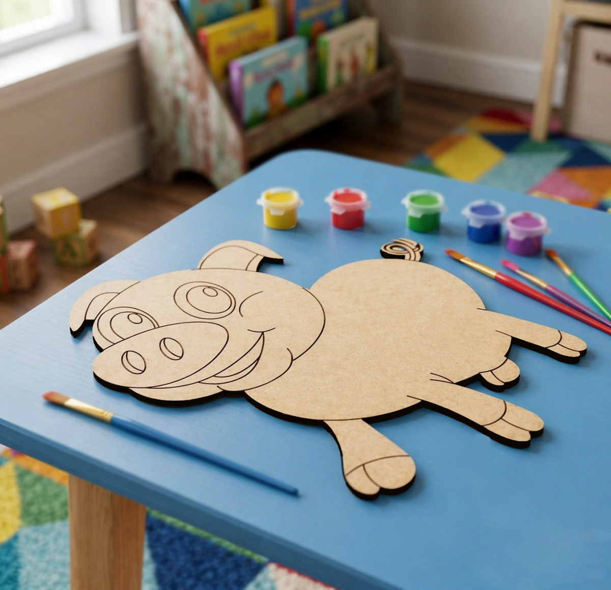 DIY MDF  pig craft on a blue table with paint supplies in a child's room.