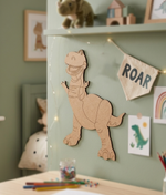 DIY MDF  dinosaur wall decoration on a light green wall with children's items around.