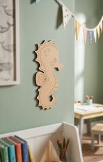 DIY MDF  seahorse decoration on a light green wall with books and a table in the background