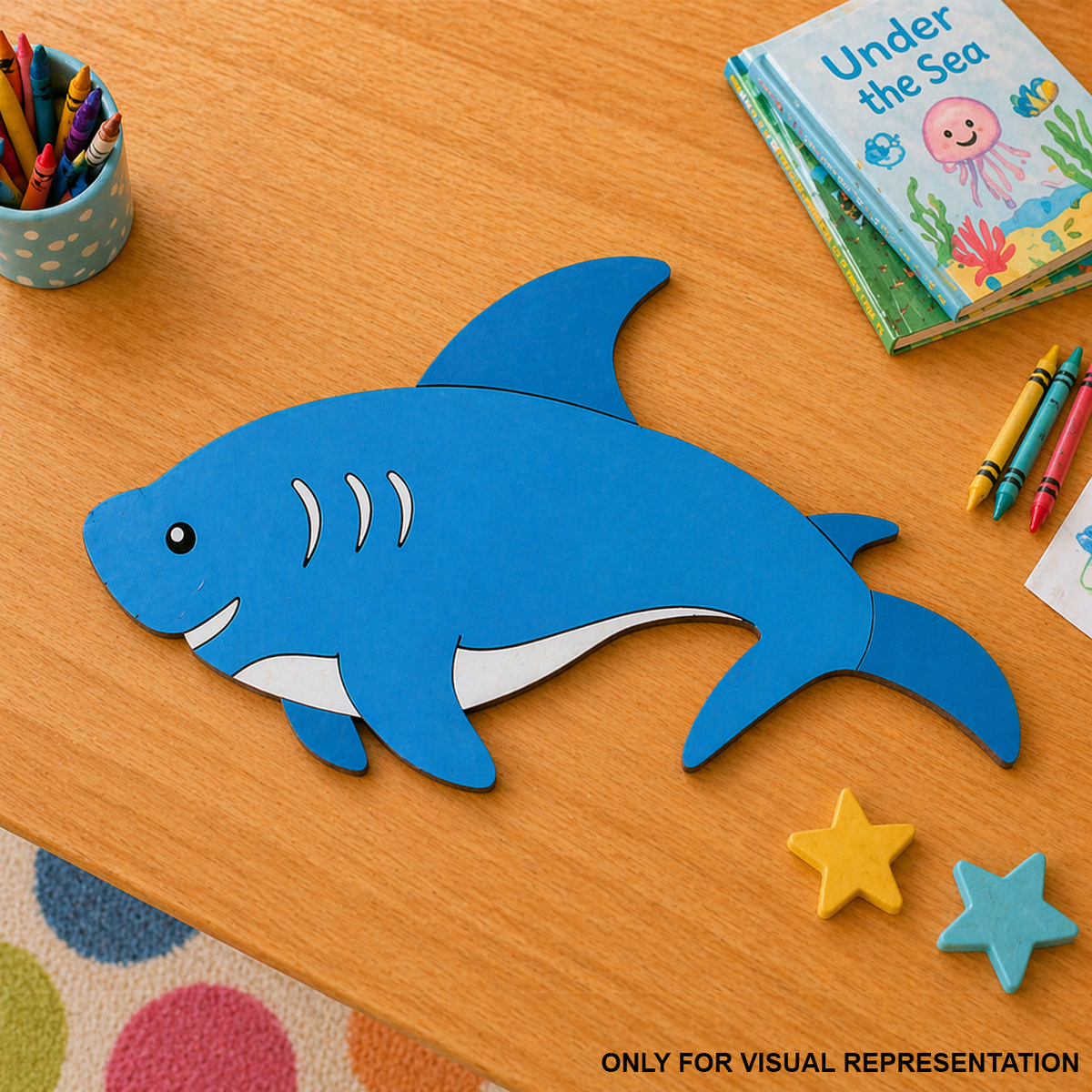 Blue DIY MDF  shark-shaped craft on a wooden table with coloring supplies and a book.