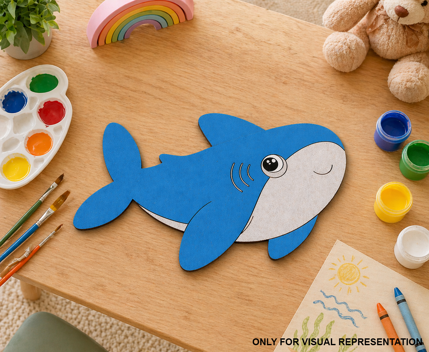 Children's craft project with a DIY MDF blue shark cutout on a wooden table, surrounded by art supplies.
