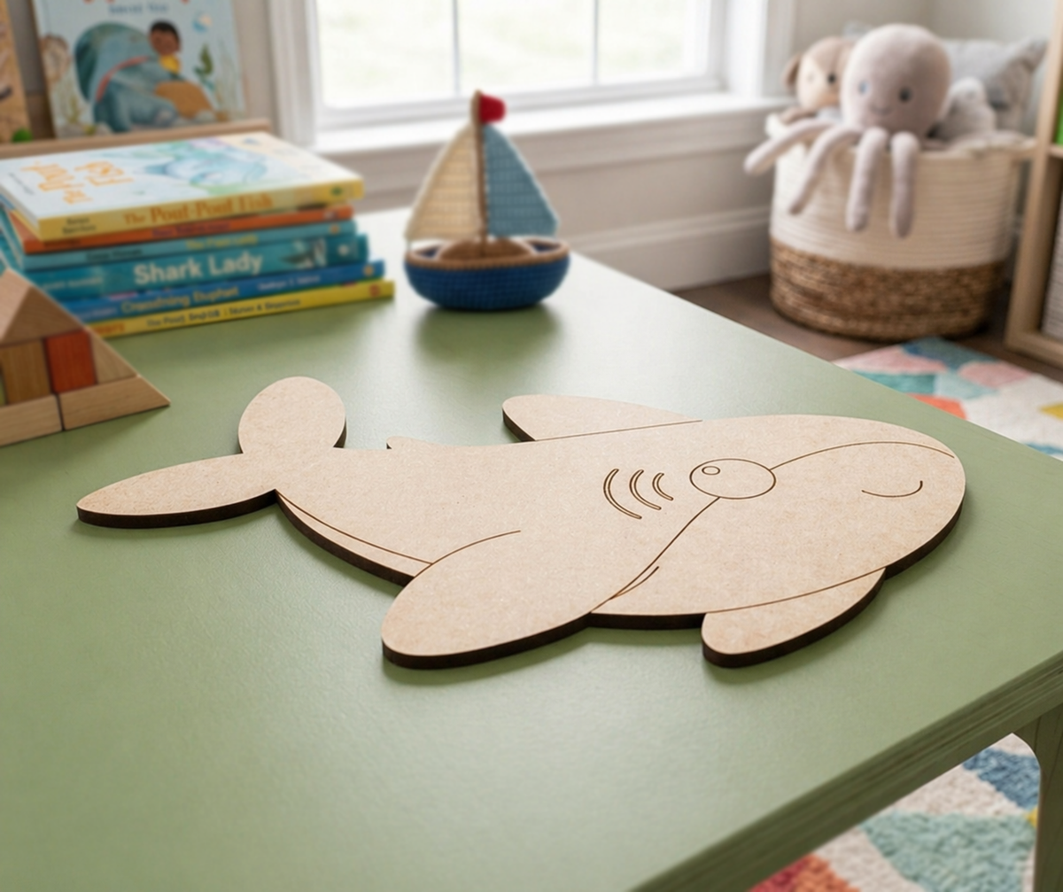 DIY MDF  shark cutout on a green table with children's books and toys in the background