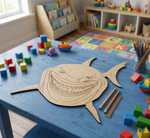 DIY MDF  shark template on a blue table with colorful toys and books in the background