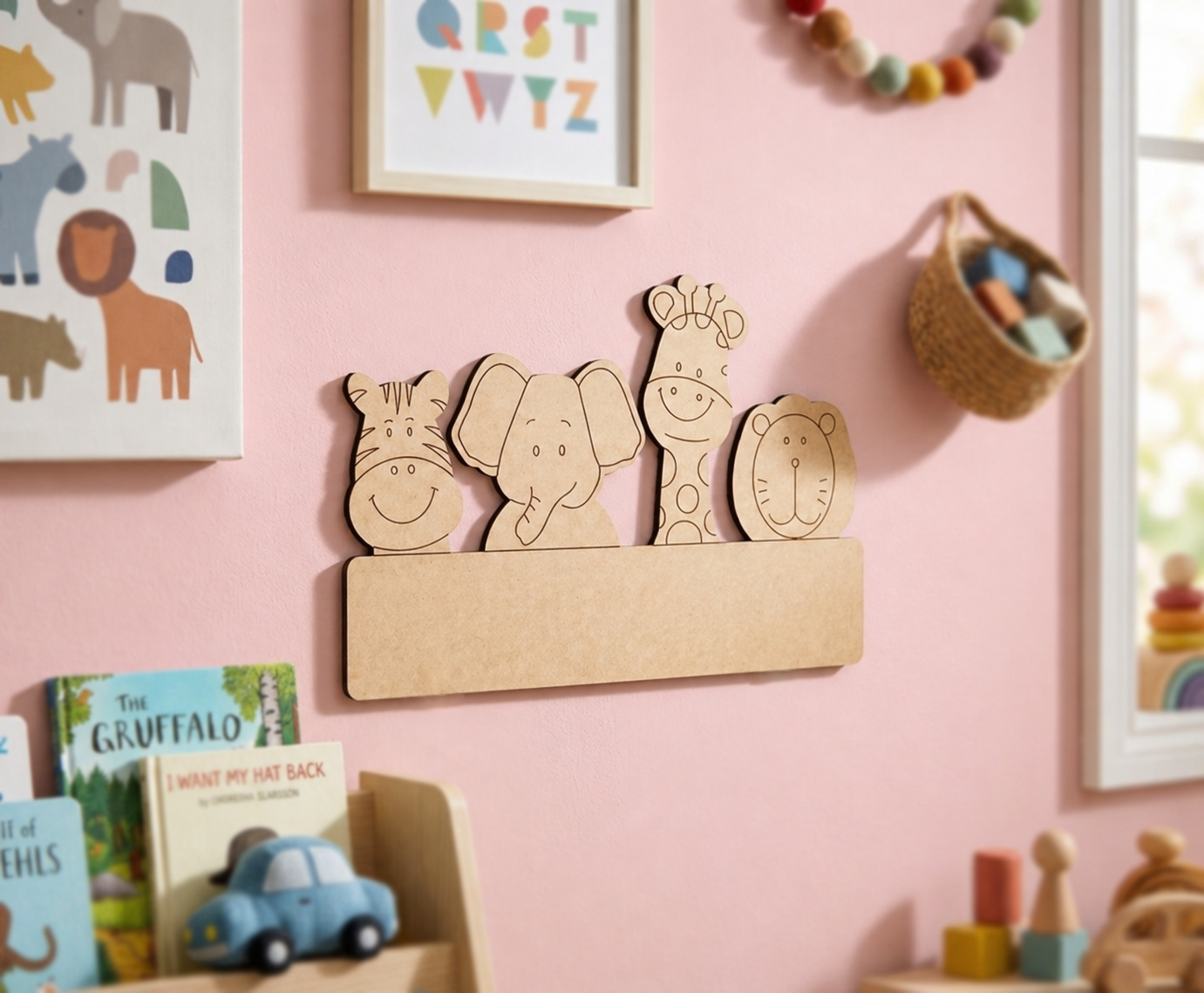 DIY MDF  wall decor with animal shapes on a pink wall with children's books and toys.