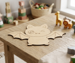 DIY MDF  bat-shaped cutout on a wooden table with toys in the background