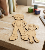 MDF DIY cutouts of a boy and his dog on a wooden surface with toys in the background.