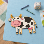 MDF DIY Cartoon cow cutout on a blue surface with crayons and a toy in the background