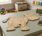 MDF DIY cow cutout on a table with toys and crayons in the background