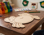 MDF DIY crab craft on a wooden table with art supplies in the background