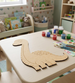 MDF DIY dinosaur template on a child's table with art supplies in a playroom.