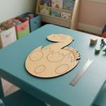 MDF DIY  craft project on a teal table with a ruler, in a room with children's books and toys.