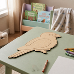 Children's play area with a MDF DIY parrot cutout on a green table, surrounded by toys and art supplies.