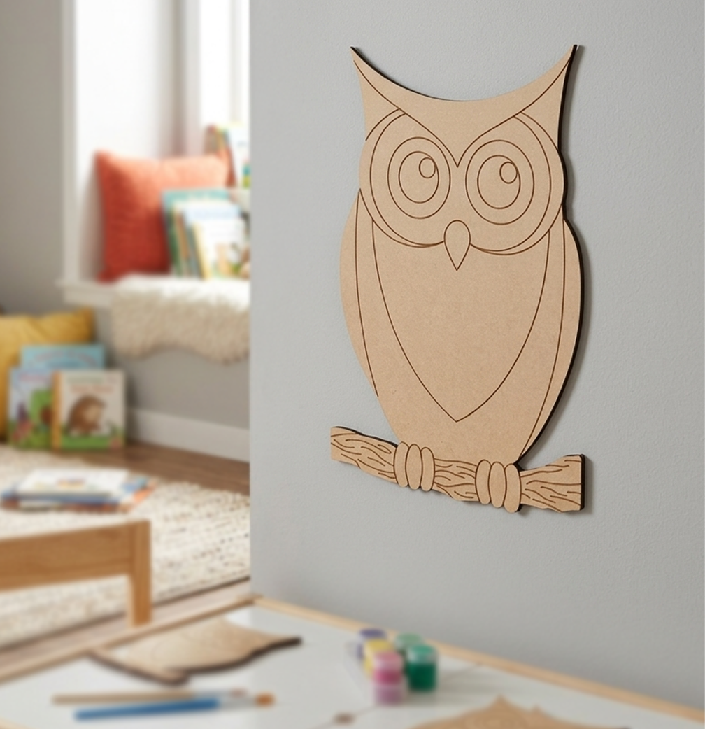 MDF DIY owl cutout hanging on grey wall.
