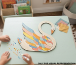 Colorful MDF DIY  swan-shaped puzzle on a table with children's hands and books in the background