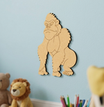 MDF DIY gorilla wall decoration on a light blue wall with toys and stationery items below.