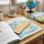 Open book with a map on a wooden desk with MDF DIY  bookmark, surrounded by stationery items.