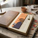 Open book with a MDF DIY bookmark on a wooden table, surrounded by a cup of tea and a lamp.