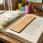 MDF DIY  bookmark with a design on an open book with stationery items in the background.