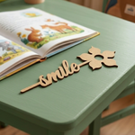  MDF DIY  bookmark 'smile' decoration on a green surface with an open book in the background