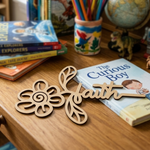 MDF DIY decorative piece with 'faith' on a wooden surface with books and stationery in the background