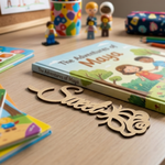 MDF DIY bookmark on a wooden surface with toys and a personalized wooden nameplate.