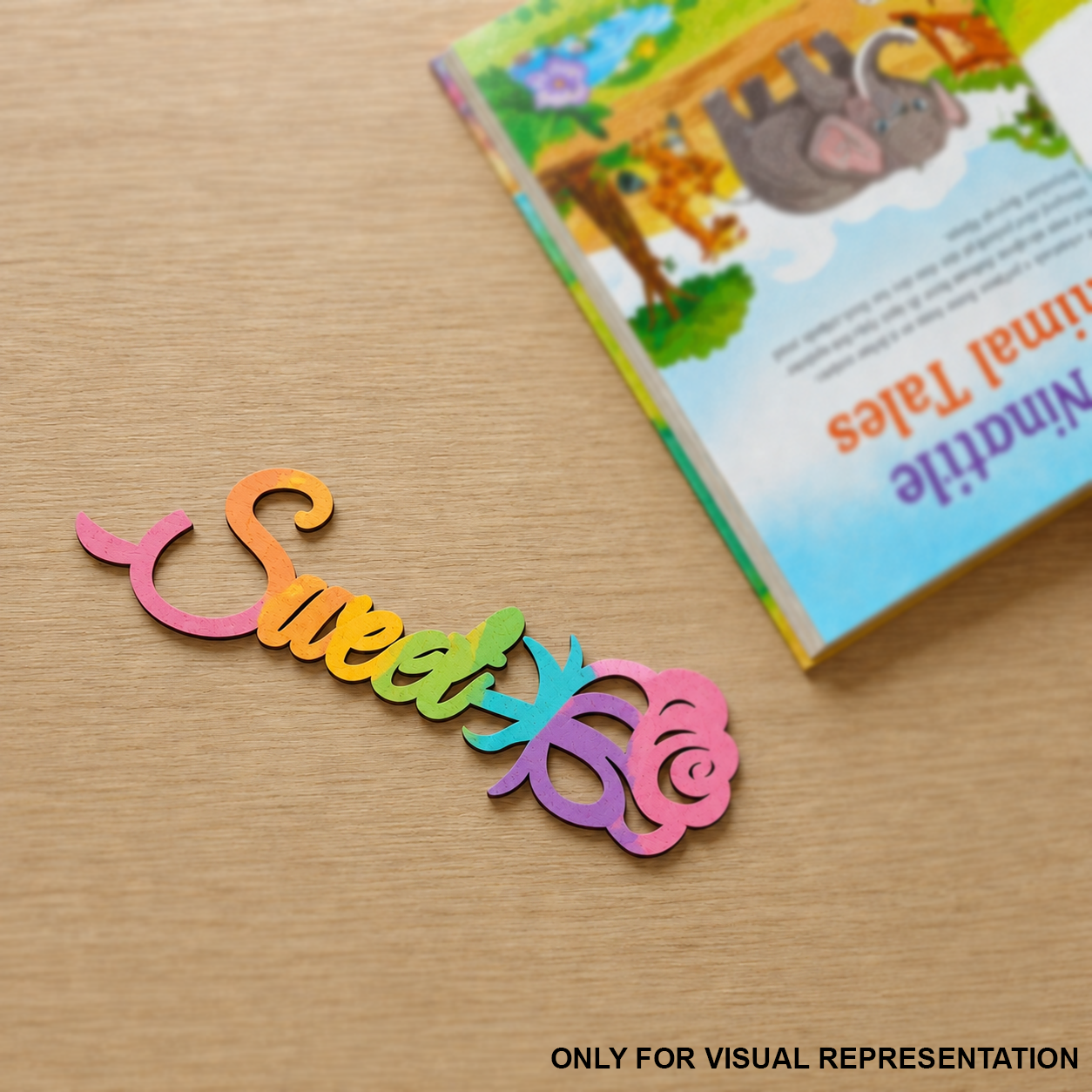 Colorful MDF DIY  'Sweet' sign on a wooden surface with a children's book in the background.