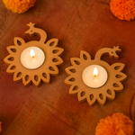 Two mdf candle holders with lit candles on an orange background