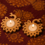 Two lit candles in decorative mdf holders on a patterned fabric background