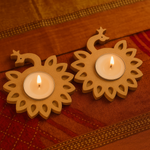 Two lit candles in decorative mdf holders on a textured surface