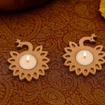 Two lit candles in decorative mdf holders on a patterned fabric background