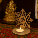 Decorative mdf candle holder with star design and 'Om' symbol, featuring a lit candle on a colorful fabric background.
