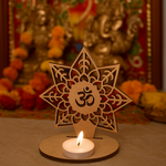 mdf decorative candle holder with a candle and Om symbol in front of a blurred religious statue.