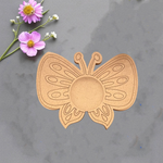 Premarked MDF butterfly-shaped tealight holder with engraved patterns, placed on grey surface with pink flowers