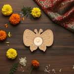 Butterfly-shaped candle holder with a lit candle on a wooden surface surrounded by marigold flowers and rice grains.