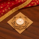Decorative tealight candle holder with a lit candle on a wooden surface with red and gold fabric in the background.