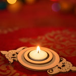 Decorative mdf candle holder with a lit candle on a red fabric background