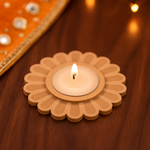 Floral-shaped candle holder with a lit candle on a wooden surface