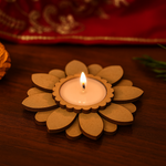 Floral-shaped mdf candle holder with a lit candle on a wooden surface.