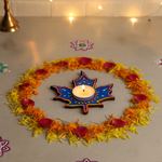 Decorative candle holder with a lit candle surrounded by flowers on a table.