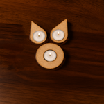  MDF tea light holder with four lit candles in leaf design on wooden background