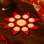 Decorative candle holder with red triangular shelves holding lit candles on a wooden surface.