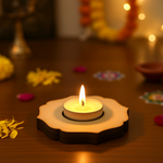 Candle in a decorative MDF Tealight holder on a wooden surface with blurred lights and decorations in the background
