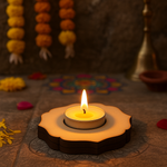 Candle in a decorative MDF tealight candle holder with flowers and lights in the background