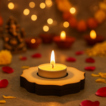 Candle in a decorative MDF Tealight candle holder with blurred lights and flowers in the background