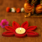Handpainted Red flower-shaped candle holder with a lit candle on a wooden surface, with blurred colorful objects in the background.
